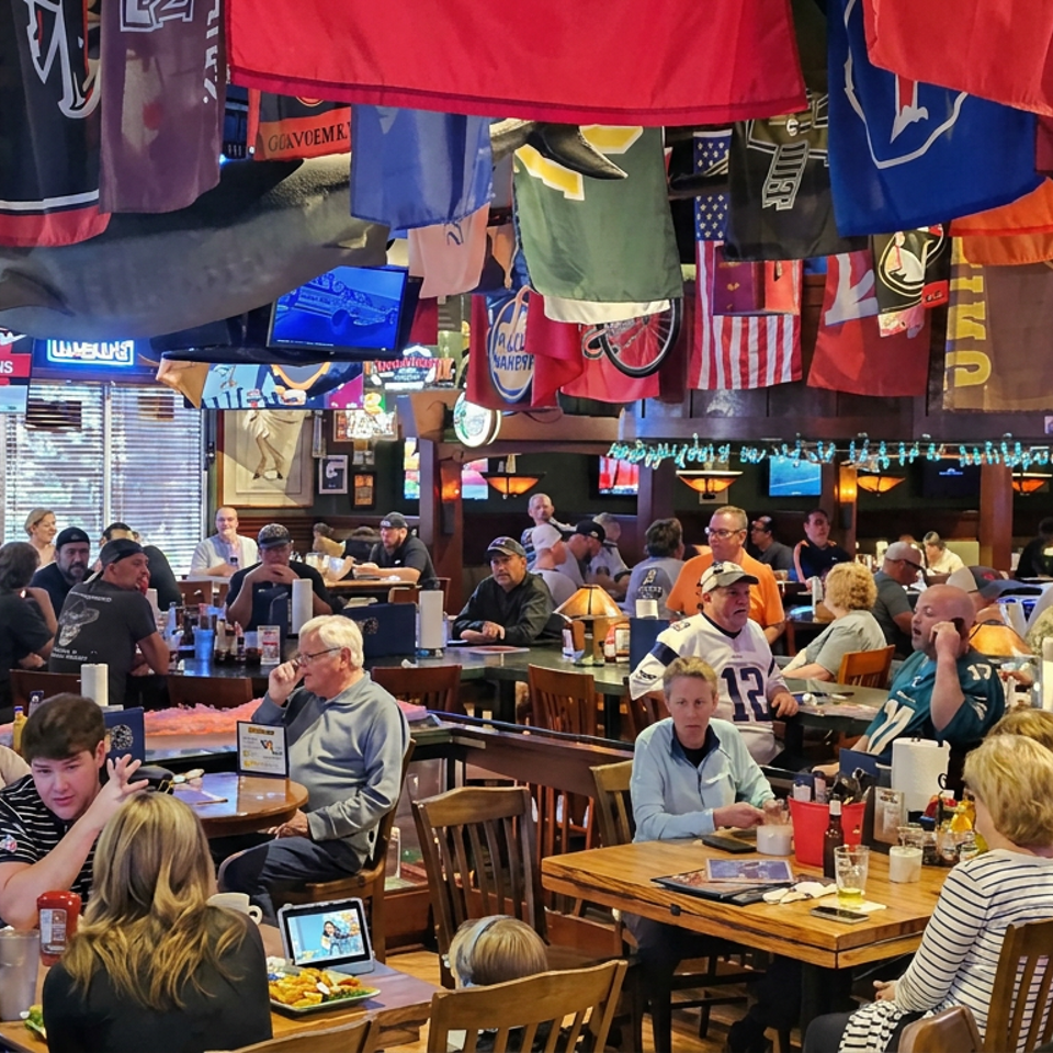 Busy sports bar filled with diners, hanging team jerseys, flags, and multiple televisions broadcasting games.